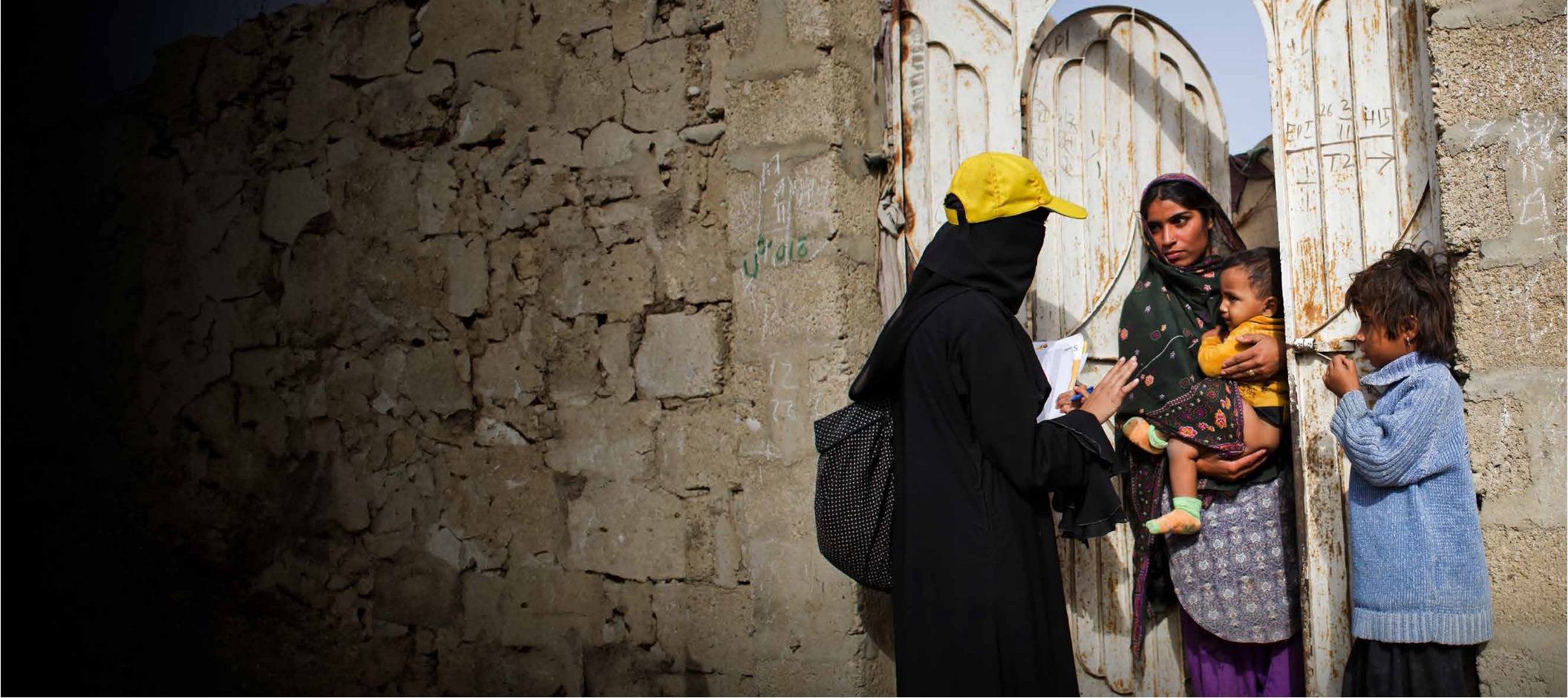 A woman talking to a mother of two at their door