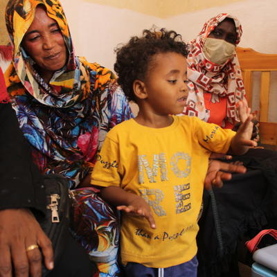 A young child proudly shows his finger after receiving a vaccination, surrounded by family members who smile in support. The moment highlights the child’s participation in the vaccination process and the positive involvement of his family in promoting health and well-being.