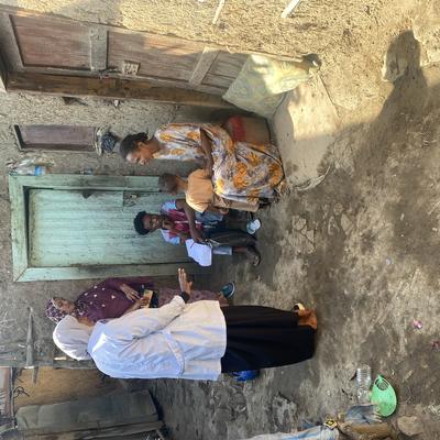A health worker engages with a family outside their home to raise awareness about immunization.