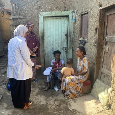 A health worker engages with a family outside their home to raise awareness about immunization.