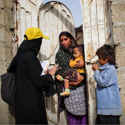 A woman talking to a mother of two at their door