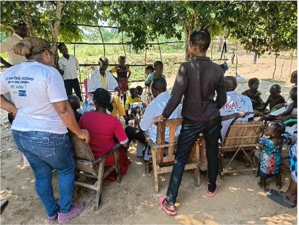 A local health meeting takes place outdoors, with villagers gathered to discuss the importance of immunization and health initiatives.