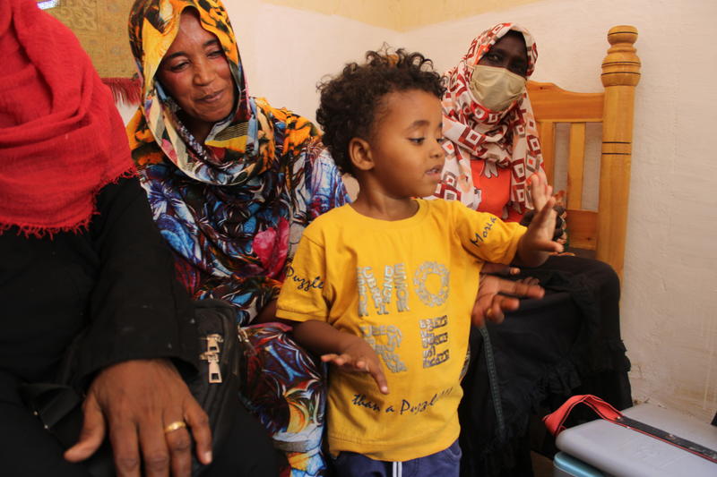A young child proudly shows his finger after receiving a vaccination, surrounded by family members who smile in support. The moment highlights the child’s participation in the vaccination process and the positive involvement of his family in promoting health and well-being.