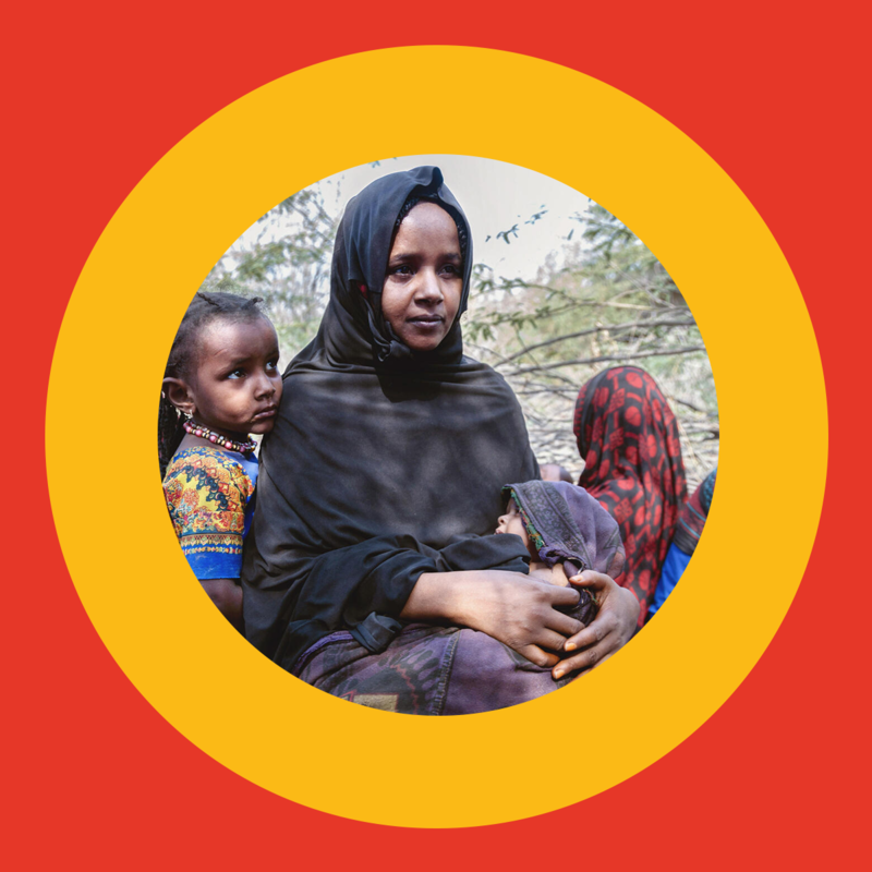 Woman holding a baby with her other child behind her