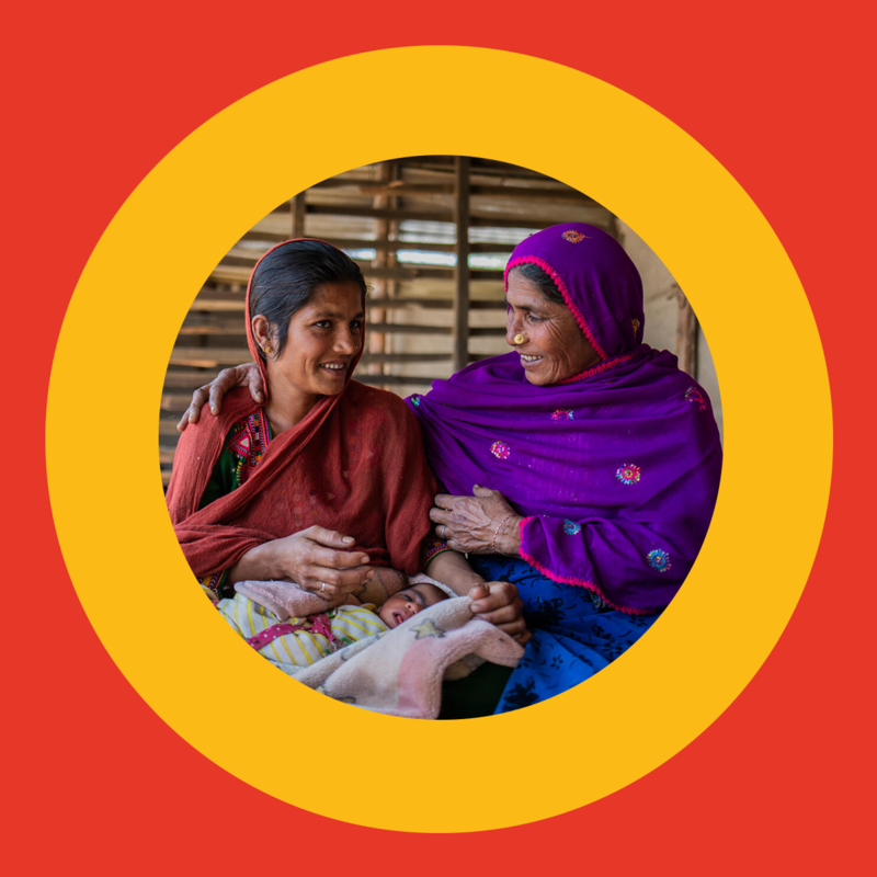 Two women smiling—one holding a baby