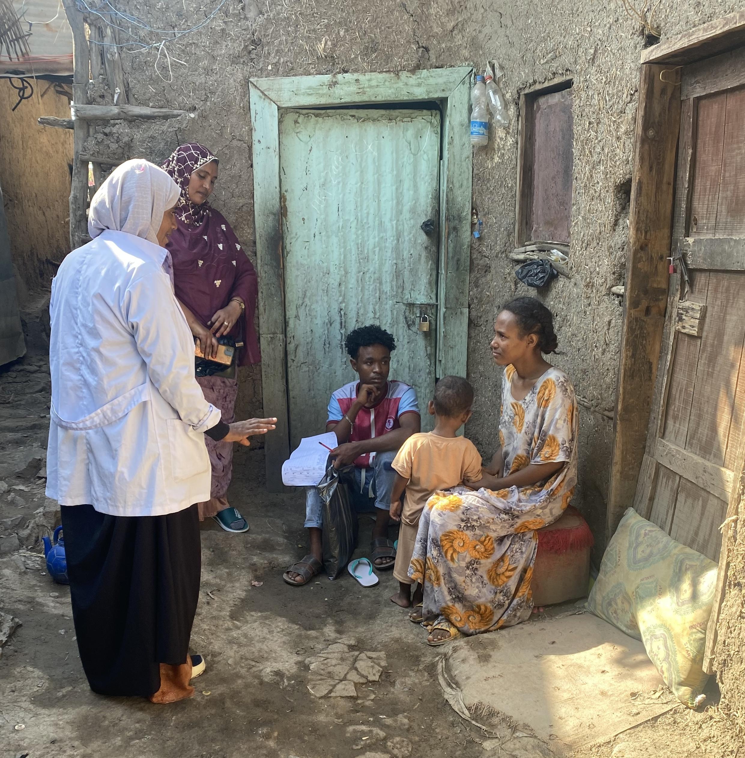 A health worker engages with a family outside their home to raise awareness about immunization.
