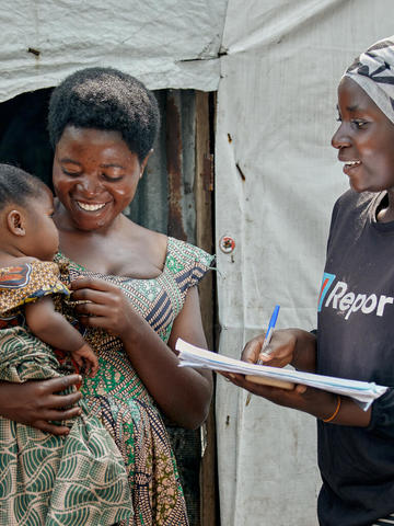 Mother holding her baby and a volunteer taking their information